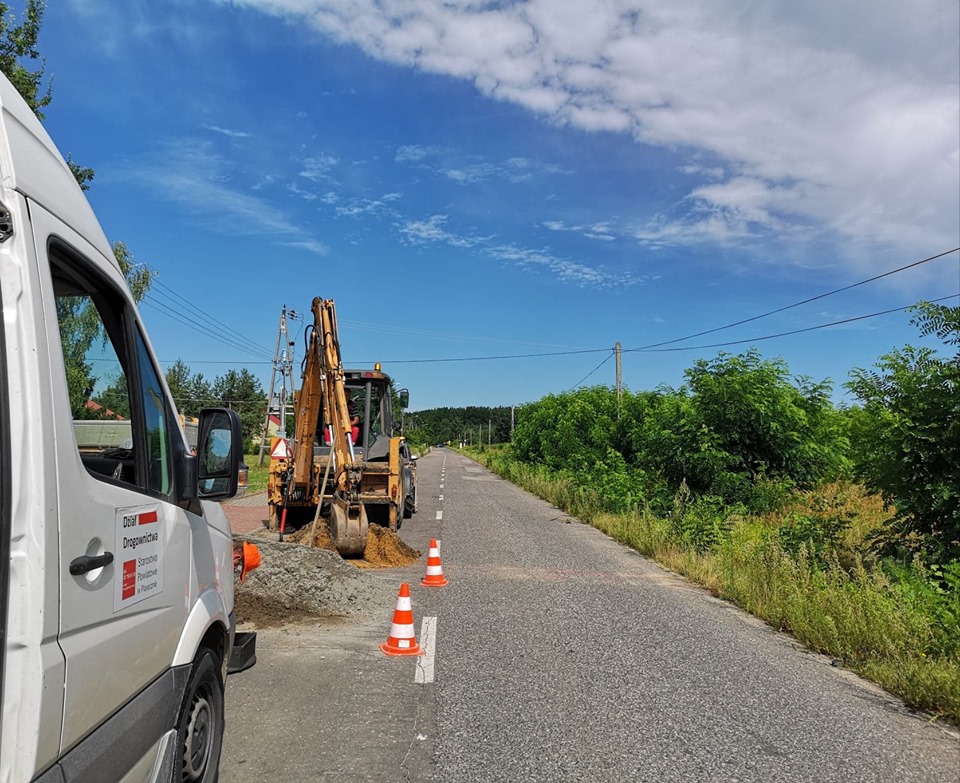 Samochód służb drogowych oraz koparka ustawione na remontowanej drodze