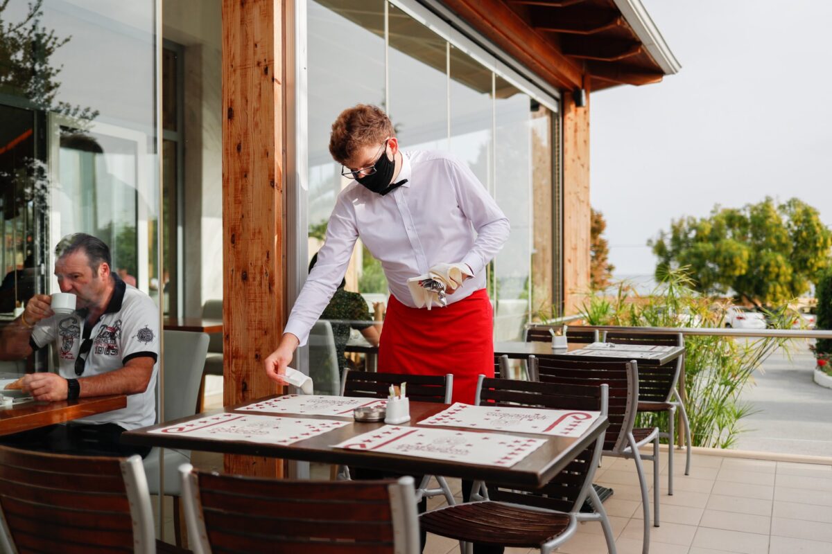 Kelner w czerwonym fartuchu nakryw do stołu