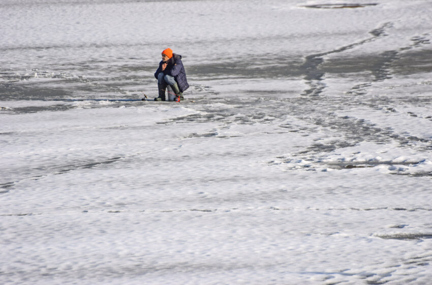 Wędkarz na środku basenu portowego siedzi na lodzie