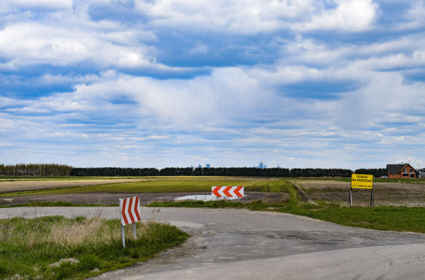 widok na skrzyżowanie dwóch dróg, w tle lesznowolskie pola oraz centrum Warszawy