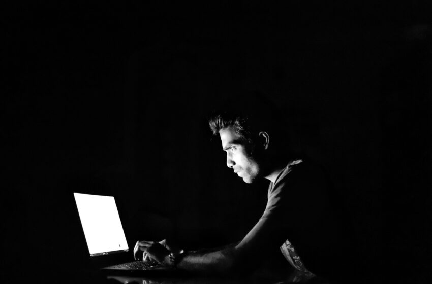 mężczyzna przed laptopem w ciemnym pomieszczeniu