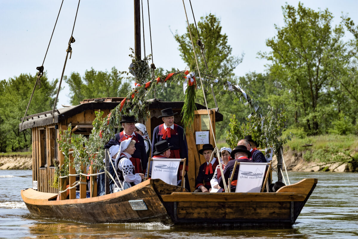 zespół ludowy na drewnianej łodzi