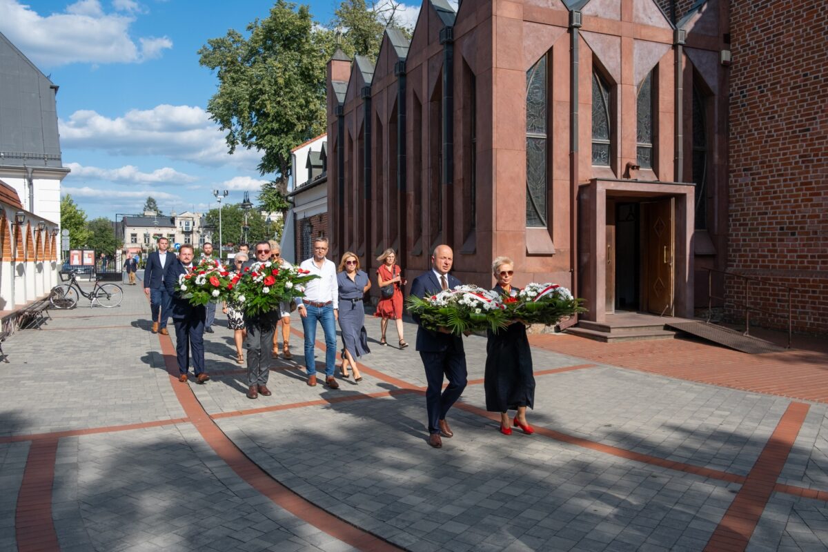 burmistrz i starosta niosą wiązanki