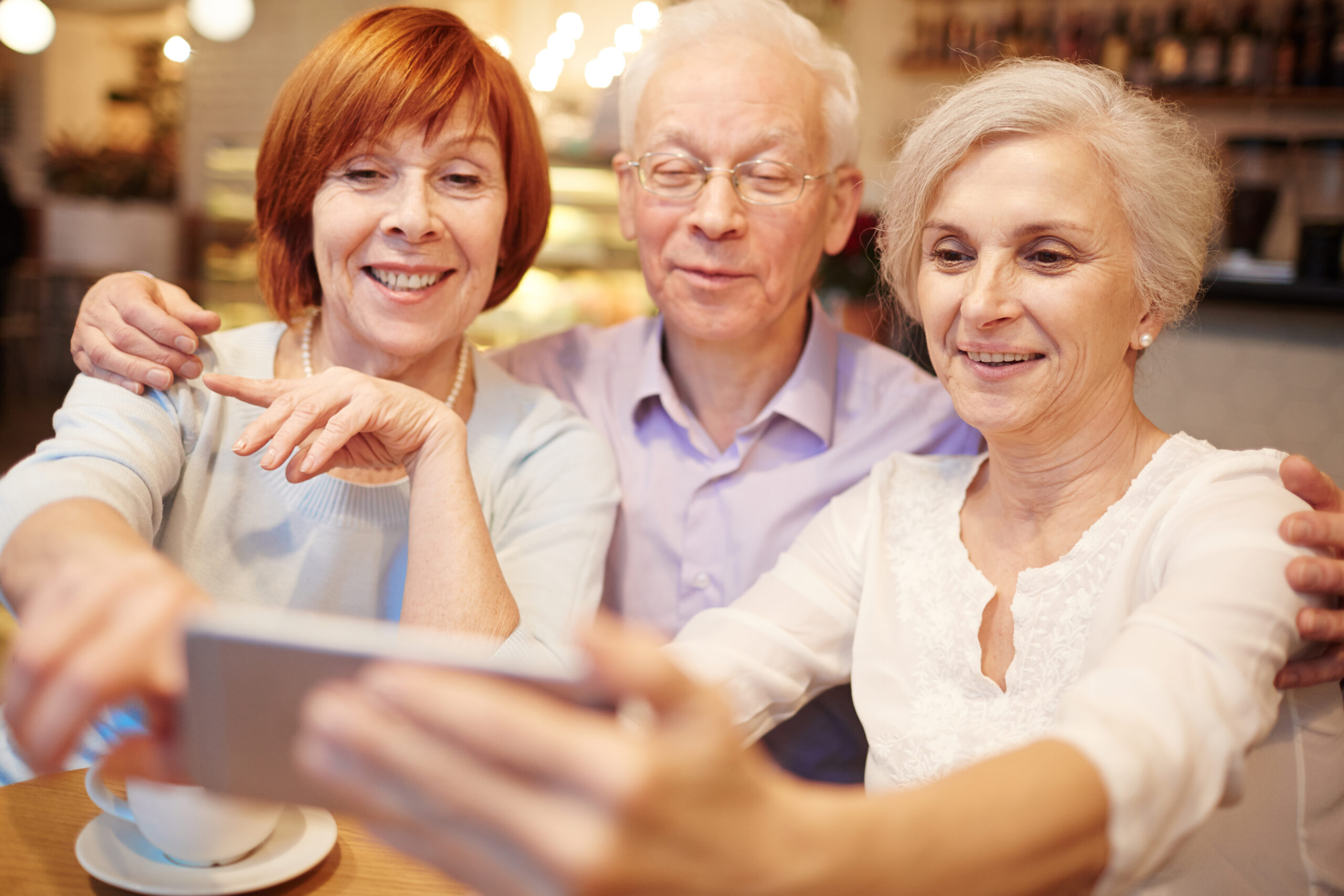 Row of smiling pensioners making their selfie in cafe during hangout