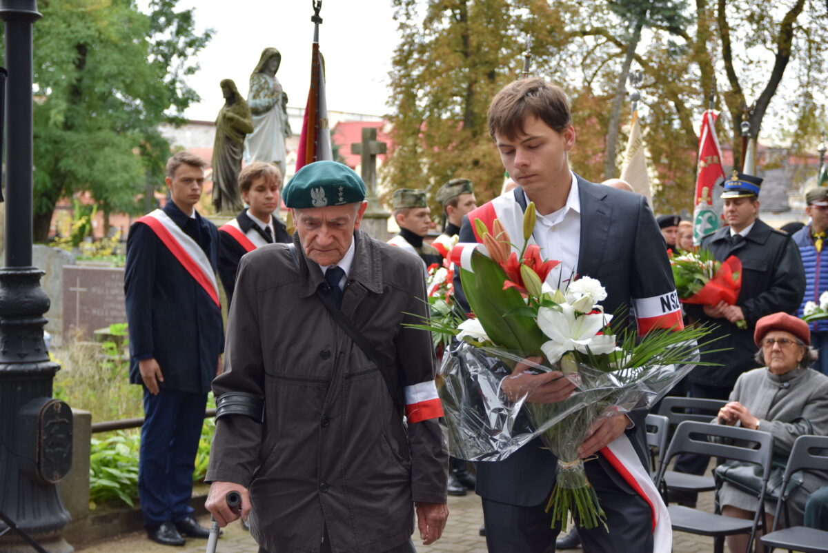 W. Sieradzki na cmentarzuy obok chłopak niesie wiązankę
